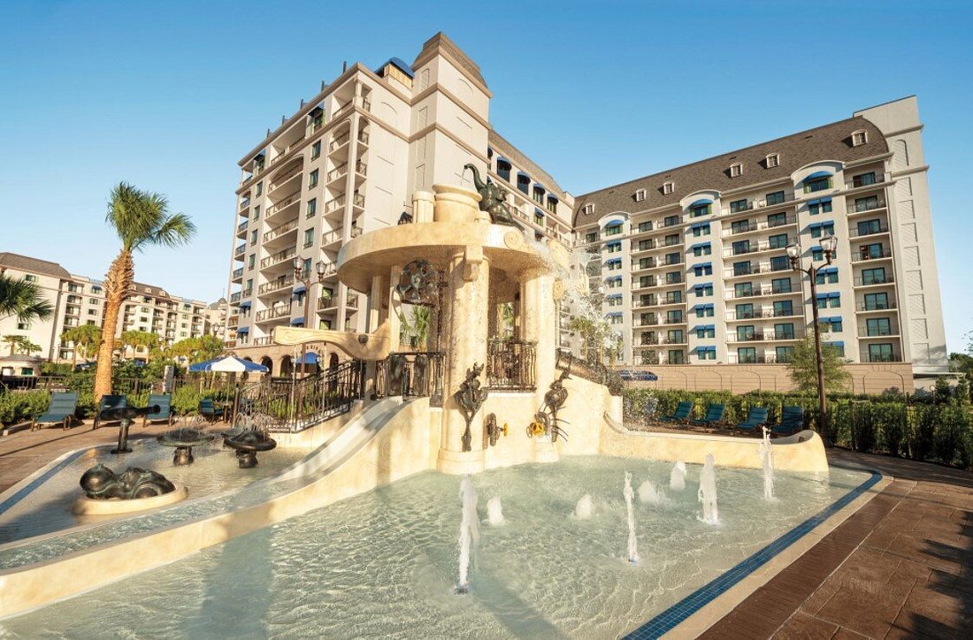 Stunning view of a Disney DVC resort pool area with palm trees and sun loungers.